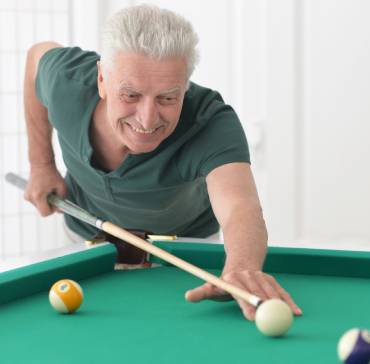 Old man playing pool in senior apartment