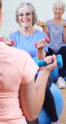 Old woman learning to lift barbell in fitness class